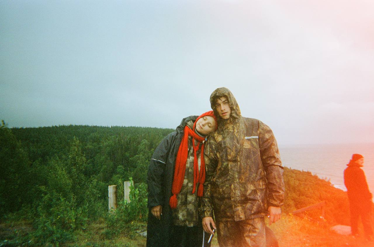 Film photo of two friends in raincoats on the cliff